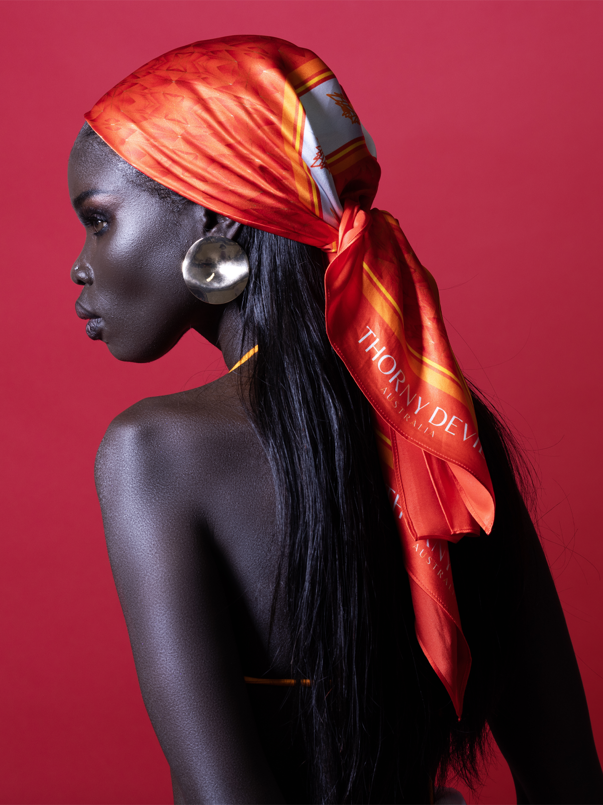 Woman wearing a red scarf with 'Thom Browne' branding against a red background